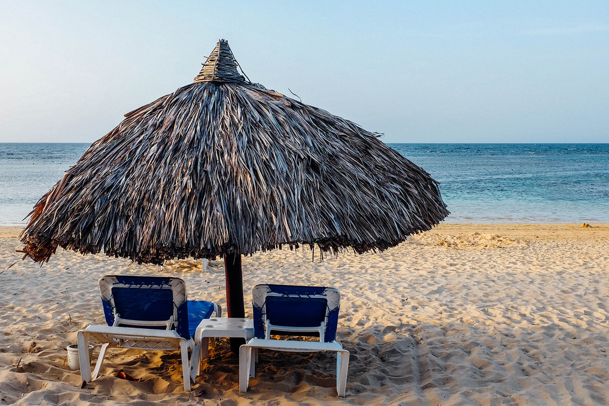 Beach loungers under a palapa ath the beach